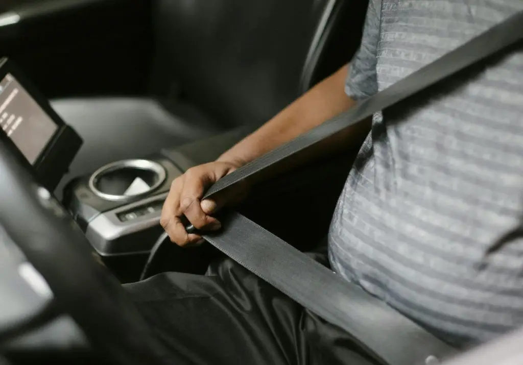 Motorist buckling up his seatbelt.